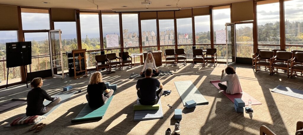 
Maren Showkier leads several attendees in yoga as morning light streams through the windows of the retreat center.