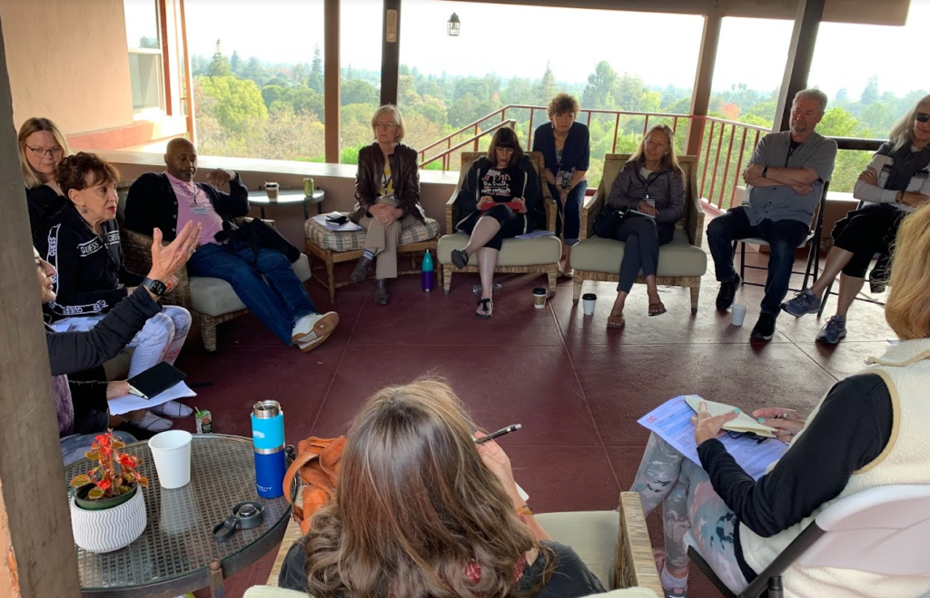  Retreat attendees gather in a covered patio and engage in a group discussion.