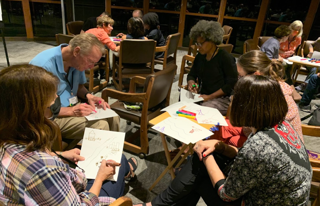  A group of five retreat members sit around a table as they draw pictures representing key moments in their lives.