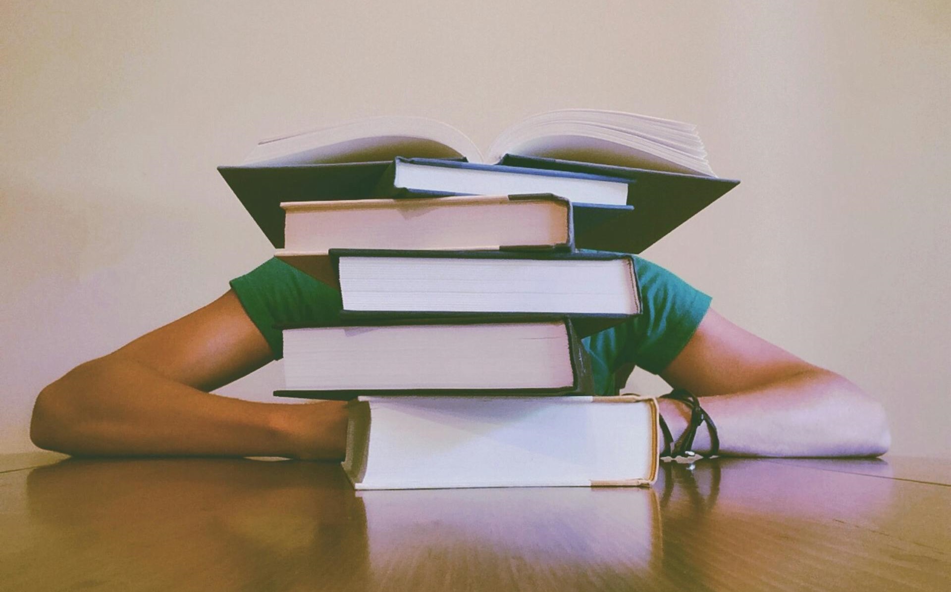 A photo of a woman whose head is hidden behind a stack of books